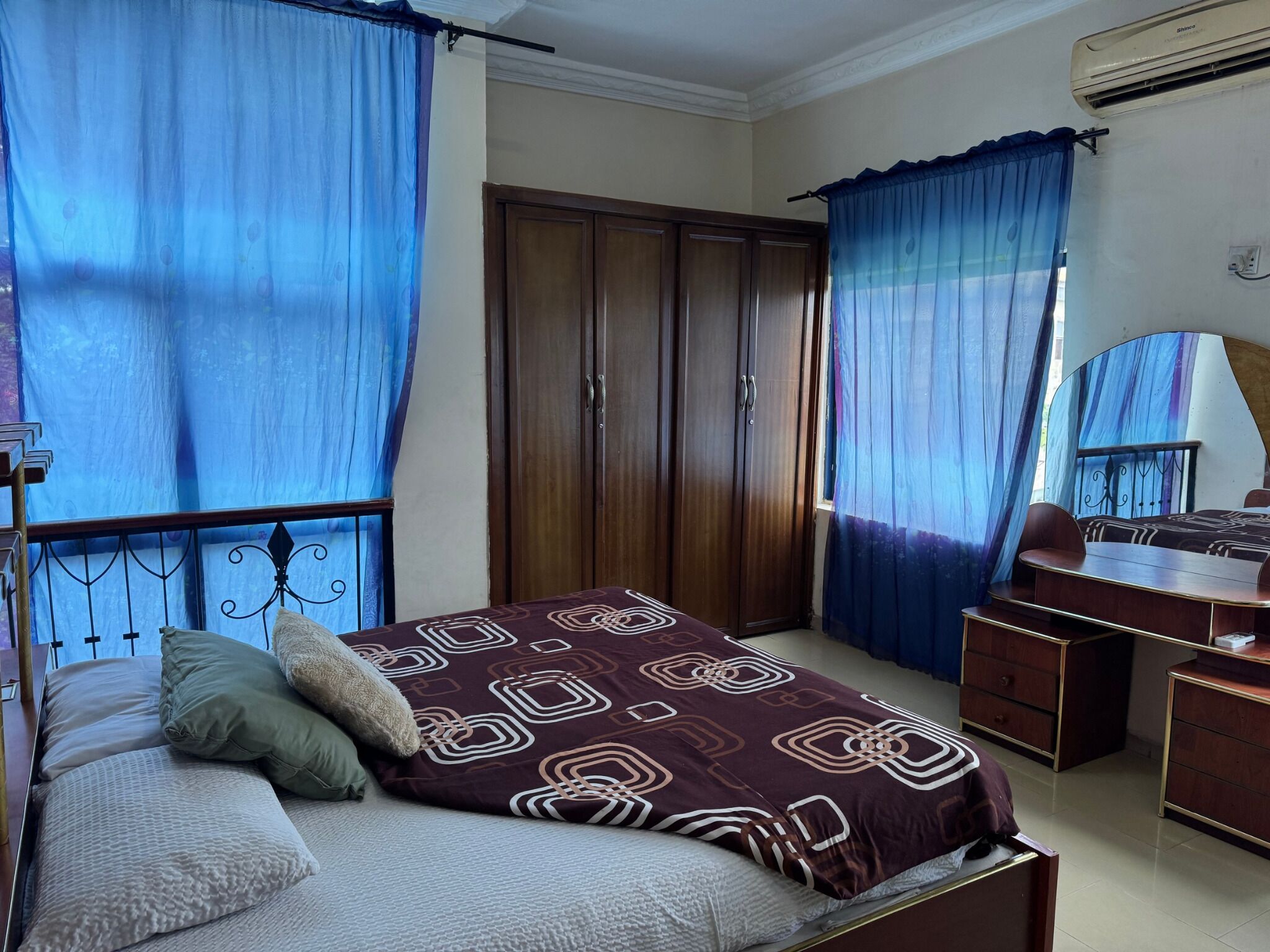 A bedroom with a bed, a desk, and a wardrobe.