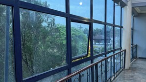 A corridor with large windows, a metal railing, and a polished floor. - Doris O Hotel  (Calabar)