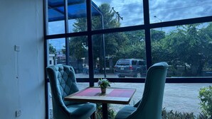 A room with large windows, two chairs, a small table, and a potted plant. - Doris O Hotel  (Calabar)
