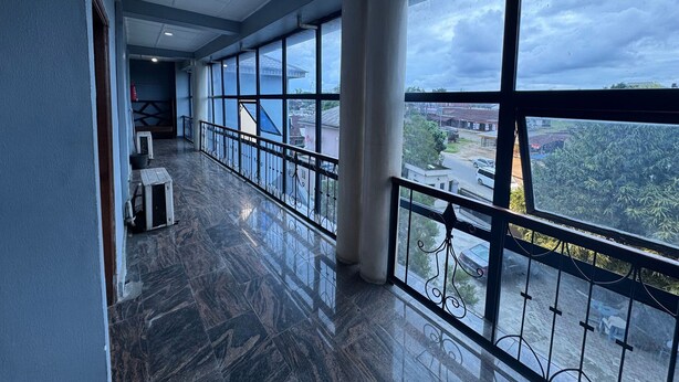 A corridor with large windows, a marble floor, and a view of the cityscape. - Doris O Hotel  (Calabar)