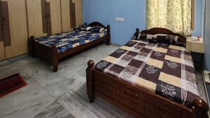 Ein Schlafzimmer mit zwei Einzelbetten, einem Deckenventilator, einer Klimaanlage und einem Fenster mit Vorhängen.