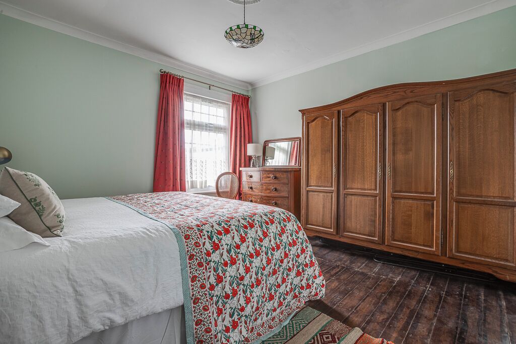 Une chambre à coucher comprenant un lit, une commode, une armoire et une fenêtre avec des rideaux.