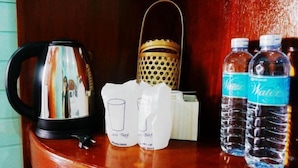 Une machine à café, une lanterne en métal et deux bouteilles d’eau sur une surface en bois.