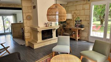 A living room with a fireplace, two chairs, a sofa, a dining table, and a large window.