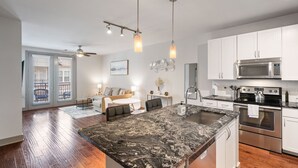 A modern kitchen with a large island, stainless steel appliances, and a dining area with a sofa and chairs.