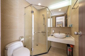 A modern bathroom with a glass-enclosed shower, a toilet, and a sink with a mirror above it.