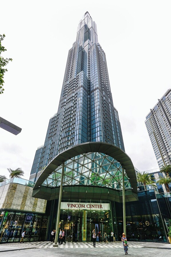 Un edificio moderno con una entrada de vidrio curvada que dice "VINCOM CENTER".