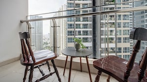 Ein Balkon mit zwei Holzstühlen, einem kleinen runden Tisch und einem Blumentopf.