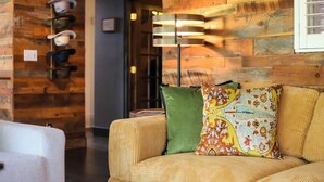 Een kamer met een houten wand, een bank met gestreepte kussens, en een wandlamp.