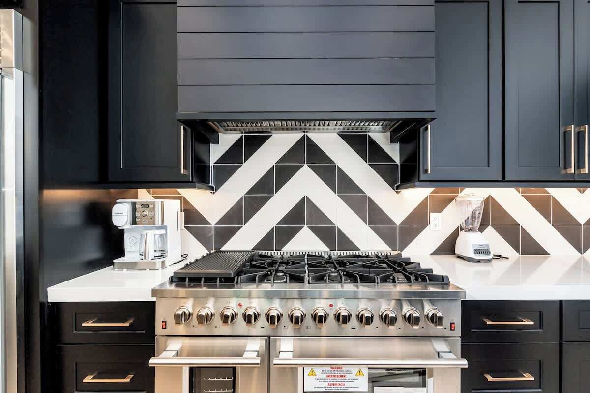 A kitchen with a gas stove, a coffee maker, and a blender.