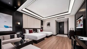 A modern hotel room with a large bed, a sofa, a desk, and a TV.