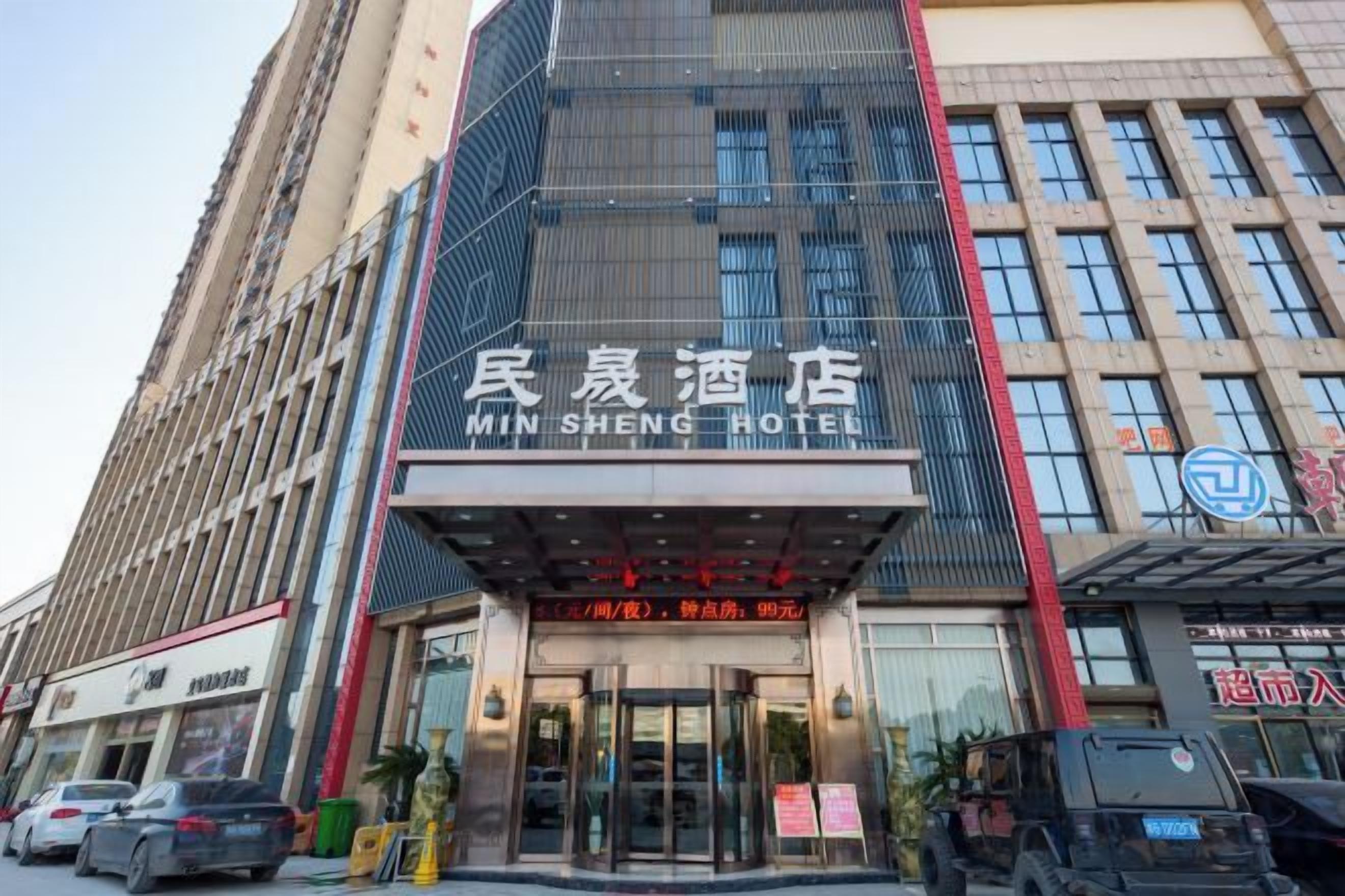A hotel with a modern facade, a prominent entrance, and a sign indicating it is the Min Sheng Hotel.