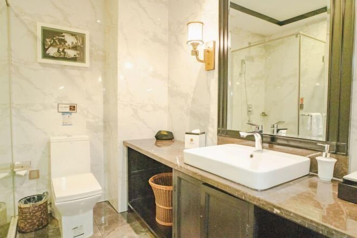 Une salle de bain avec des toilettes blanches, un lavabo avec un miroir et un espace douche.