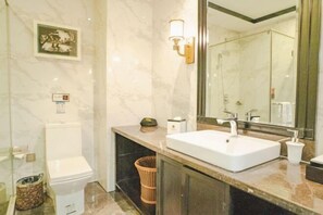 Une salle de bain avec des toilettes blanches, un lavabo avec un miroir et un espace douche.