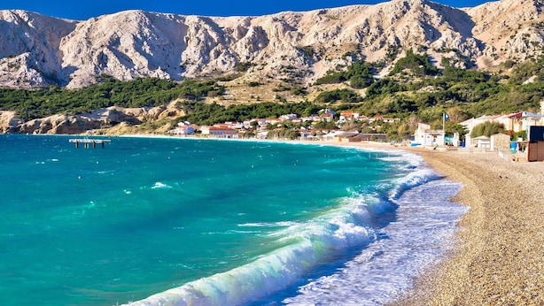 A coastal town with a beach, clear turquoise waters, and rocky mountains in the background. - Pool Apartment Sapore Di Mare 3 (Baska)