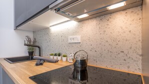 A modern kitchen with a black induction cooktop, a stainless steel kettle, and a wooden countertop. - Pool Apartment Sapore Di Mare 3 (Baska)