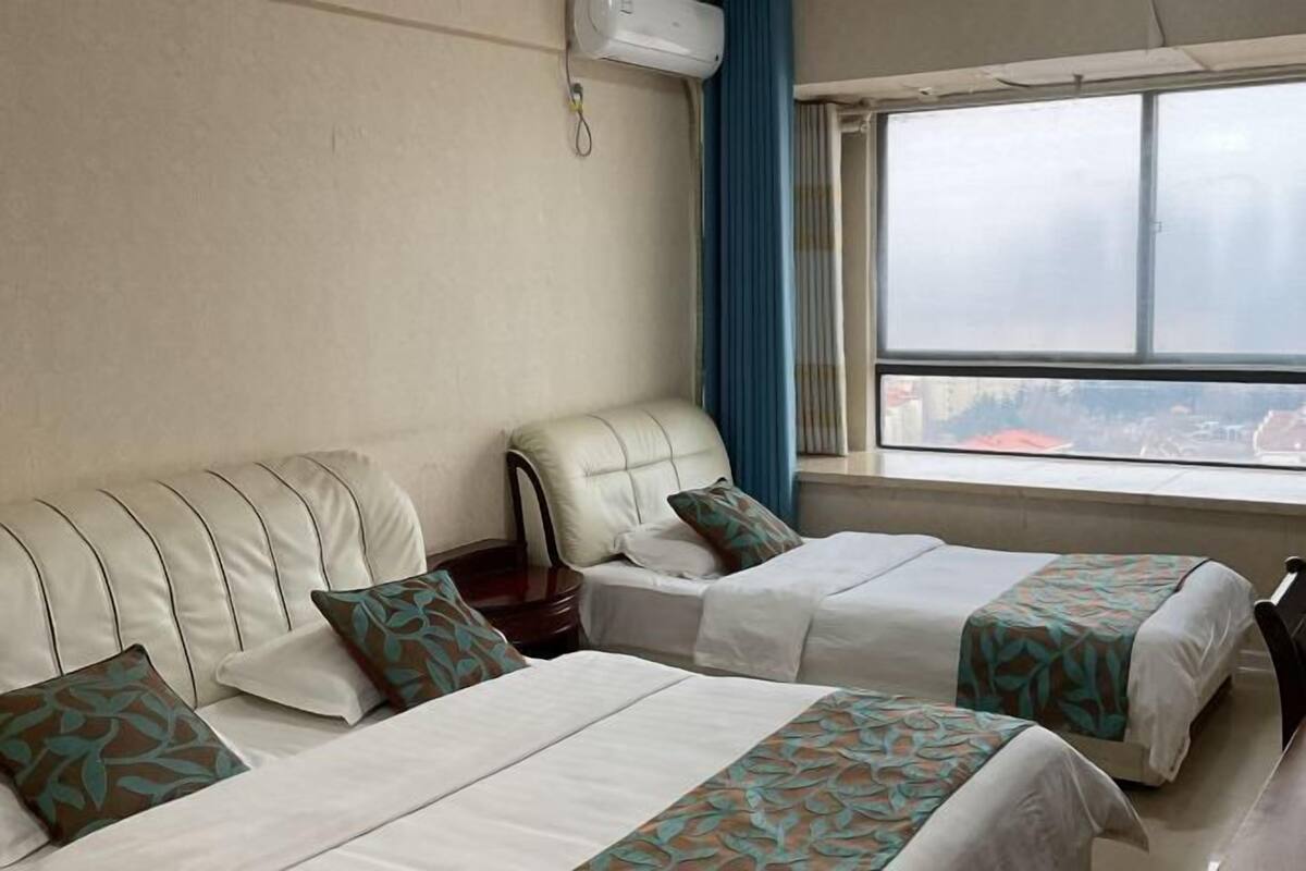 Une chambre d’hôtel avec deux lits, un canapé et une fenêtre donnant sur un beau paysage.