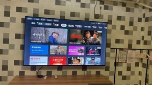 A television mounted on a wall displaying various program options. - Jiaozhou Haiyue Apartment Hotel (Jiaozhou)