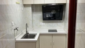 A compact kitchen with a built-in dishwasher, a sink, and light-colored cabinets. - Jiaozhou Haiyue Apartment Hotel (Jiaozhou)