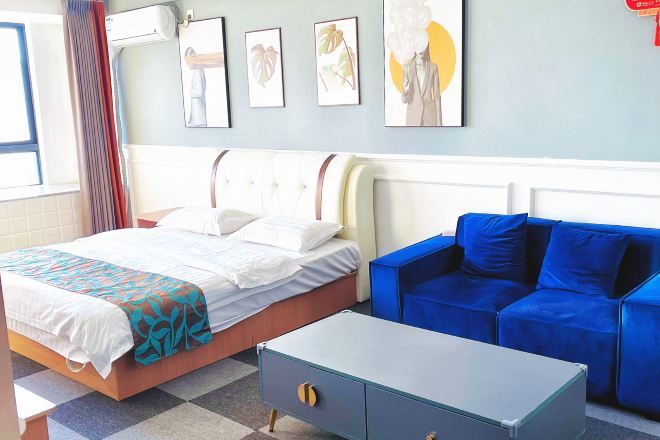 Une chambre d’hôtel avec un lit, un canapé bleu, une petite table et des œuvres d’art accrochées au mur.