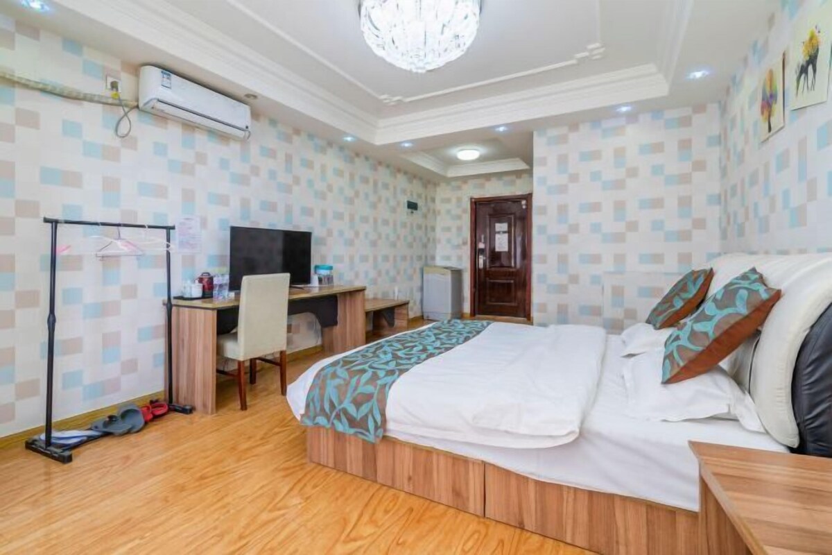 Quarto de hotel com uma cama, uma escrivaninha com cadeira, televisão e guarda-roupa.