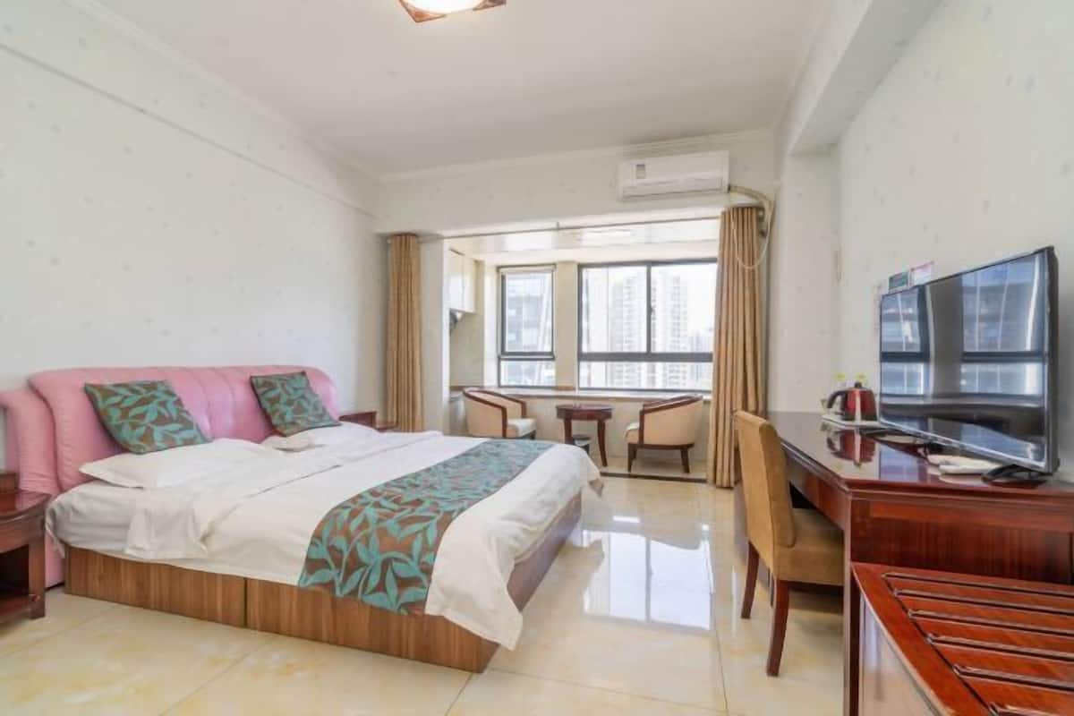 Une chambre d’hôtel avec un lit, un bureau avec une télévision, une chaise et une fenêtre donnant sur la ville.