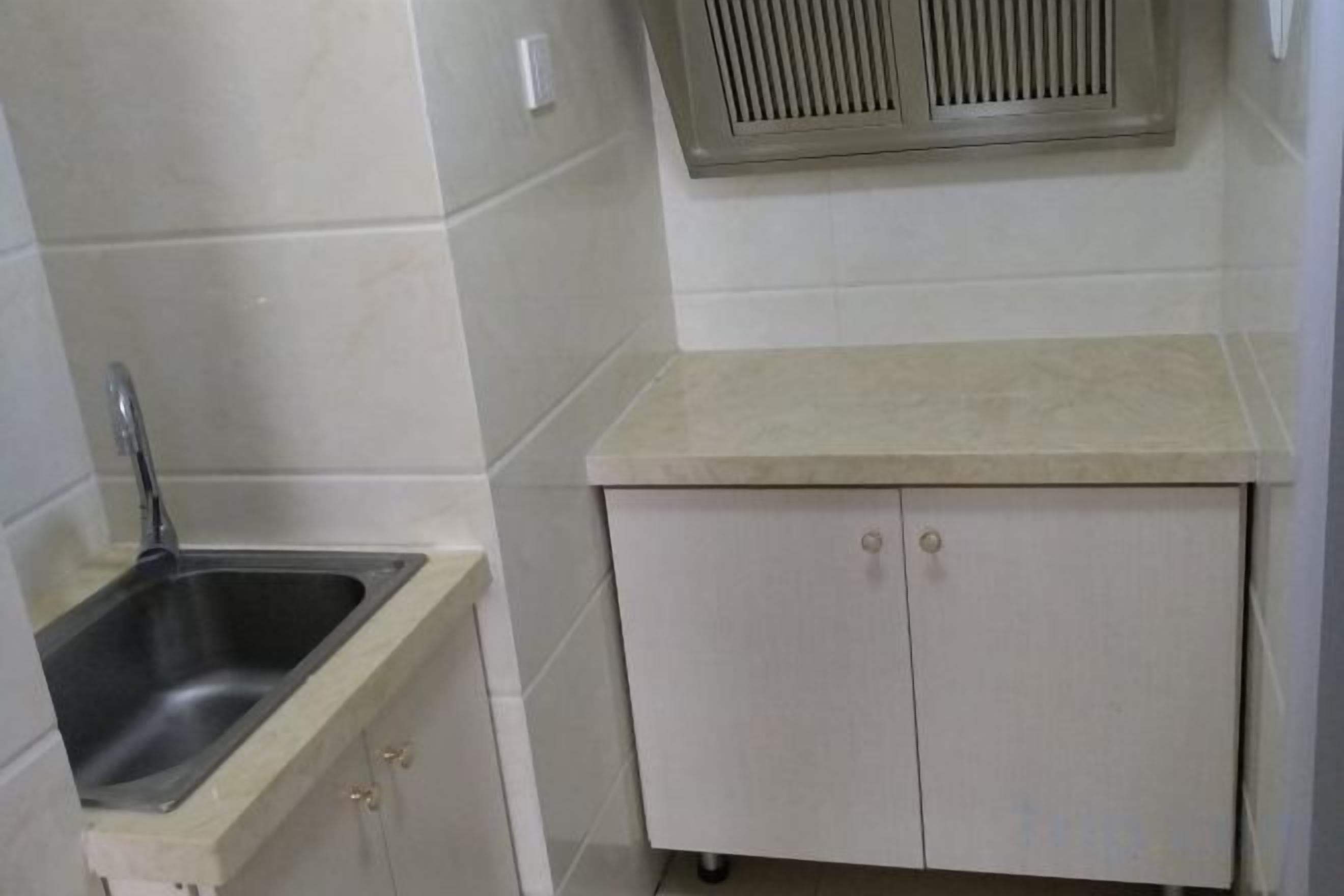 Een keuken met een spoelbak, aanrecht en kastjes.
