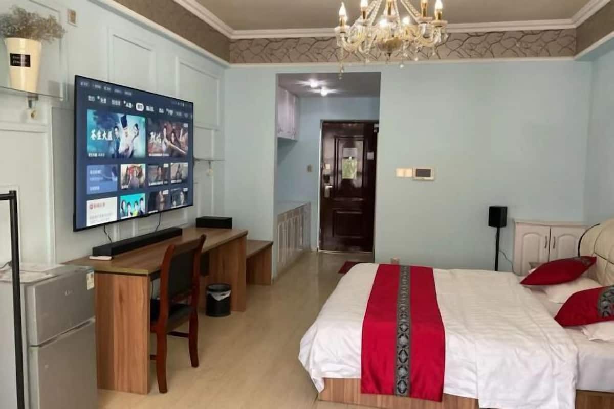 Une chambre à coucher avec un lit, un bureau, une télévision et un lustre.