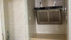 A kitchen with a stainless steel range hood, a sink, and a countertop. - Jiaozhou Haiyue Apartment Hotel (Jiaozhou)