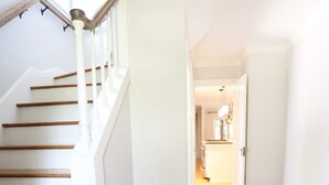 A staircase with wooden steps and white railings leading to a hallway with wooden flooring. - Purdue Bell Tower views, Central WL location, Walk 2 Purdue (West Lafayette)
