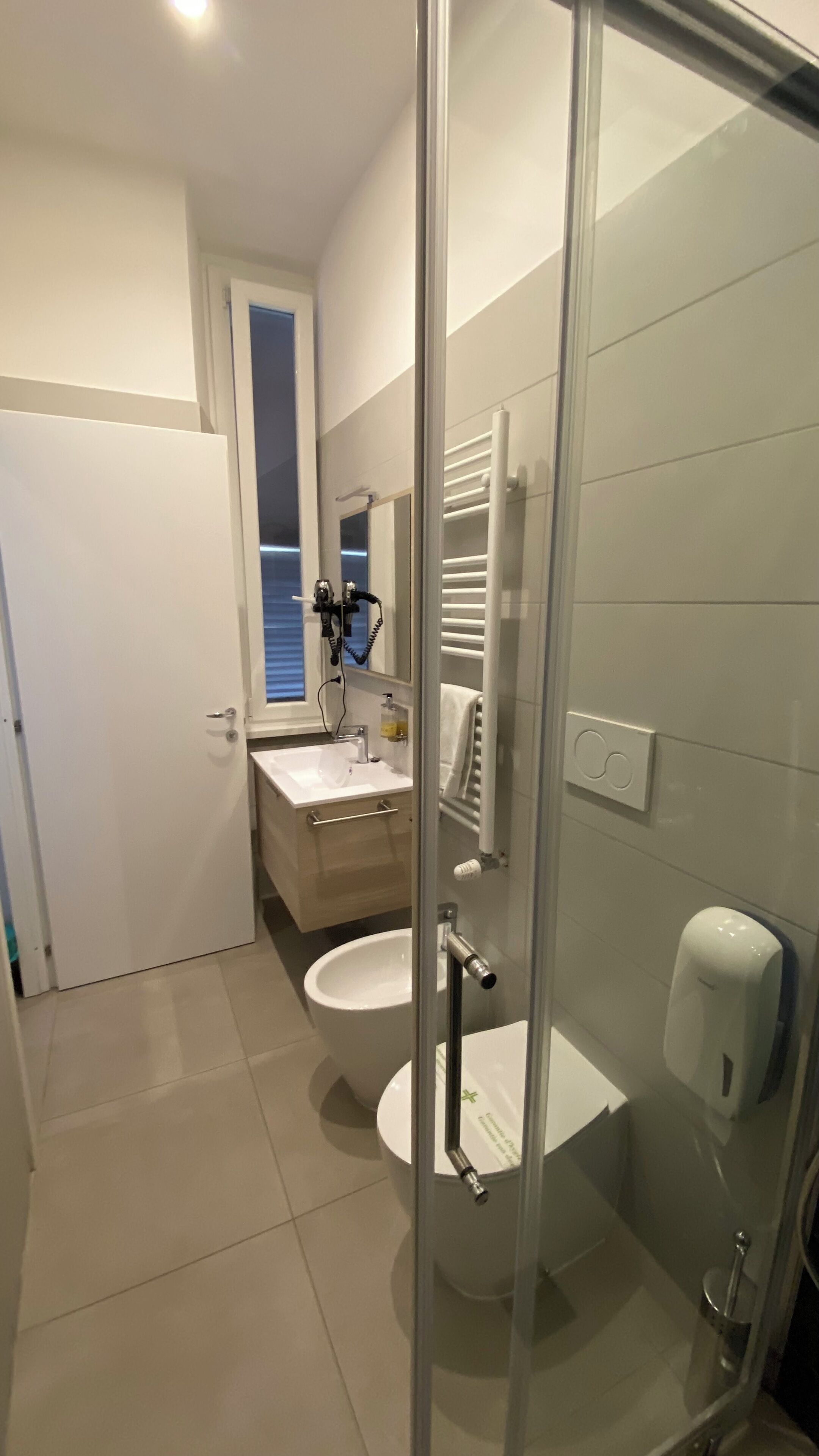 A modern bathroom with a glass shower enclosure, a toilet, a sink, and a towel rack.