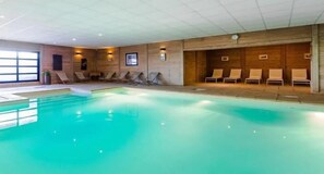 An indoor swimming pool with lounge chairs and a tiled ceiling. - 100m from ski slopes, 3rd floor, swimming pool, sauna, hammam, balcony, fireplace or stove, tv (Val Thorens)