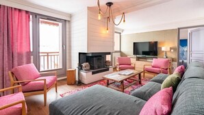 A modern living room with a fireplace, a television, and a balcony with red curtains. - 100m from ski slopes, 3rd floor, swimming pool, sauna, hammam, balcony, fireplace or stove, tv (Val Thorens)