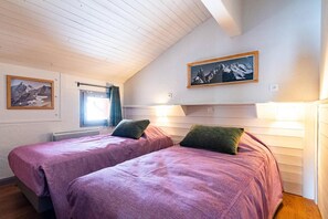 A bedroom with two beds, a window with curtains, and a painting on the wall. - 100m from ski slopes, 3rd floor, swimming pool, sauna, hammam, balcony, fireplace or stove, tv (Val Thorens)
