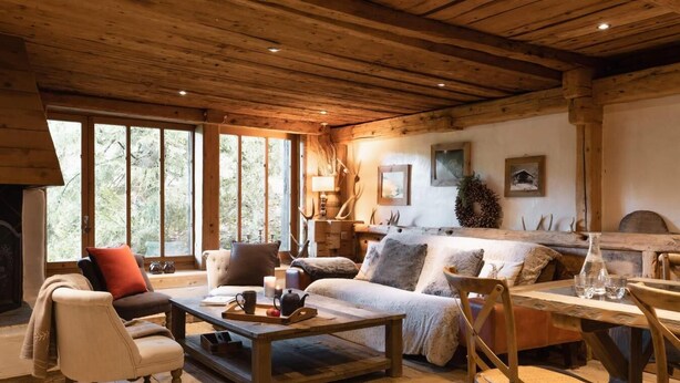 Un intérieur de chalet chaleureux avec une cheminée, des meubles en bois et de grandes fenêtres.