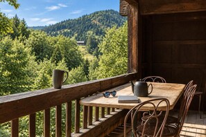 A wooden deck with a table and chairs, a kettle, a book, and a mug.