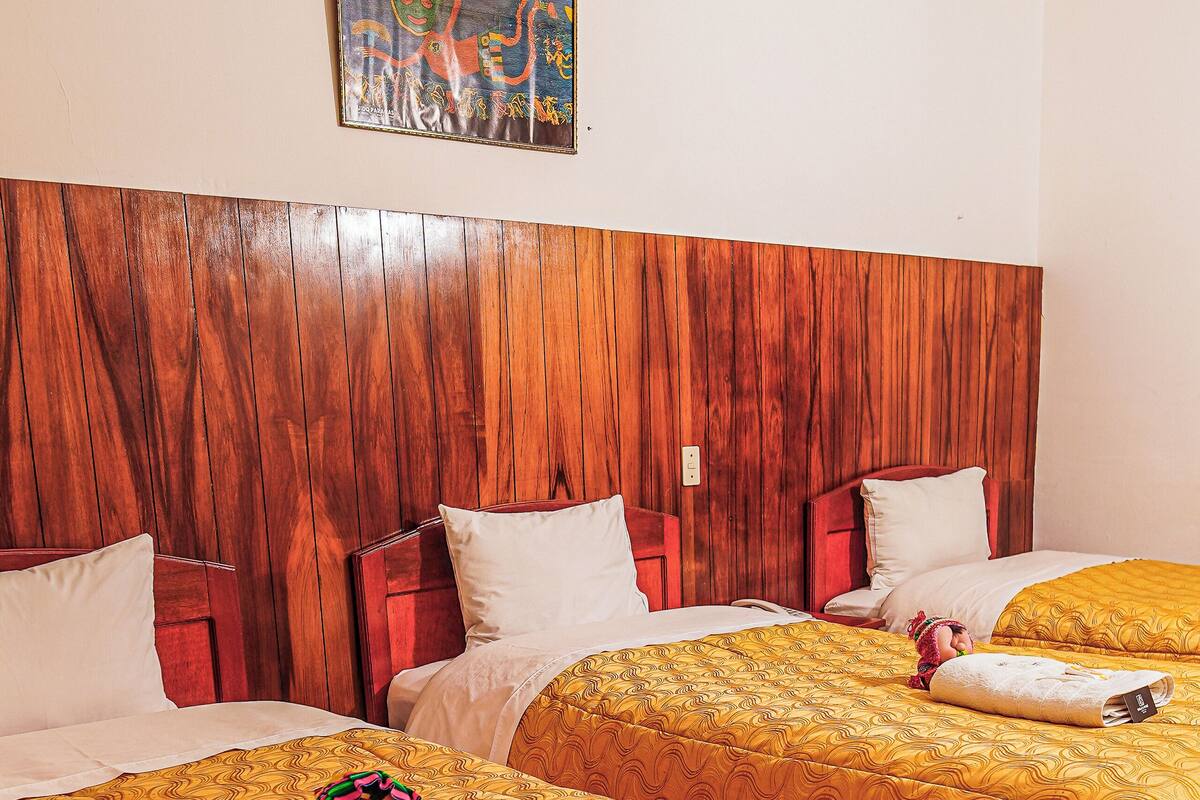 Une chambre d’hôtel avec deux lits, des têtes de lit en bois et un tableau au mur.