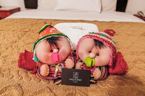 Dos muñecas sobre una cama con una tarjeta que dice "INKA'S PERU HOSTAL".