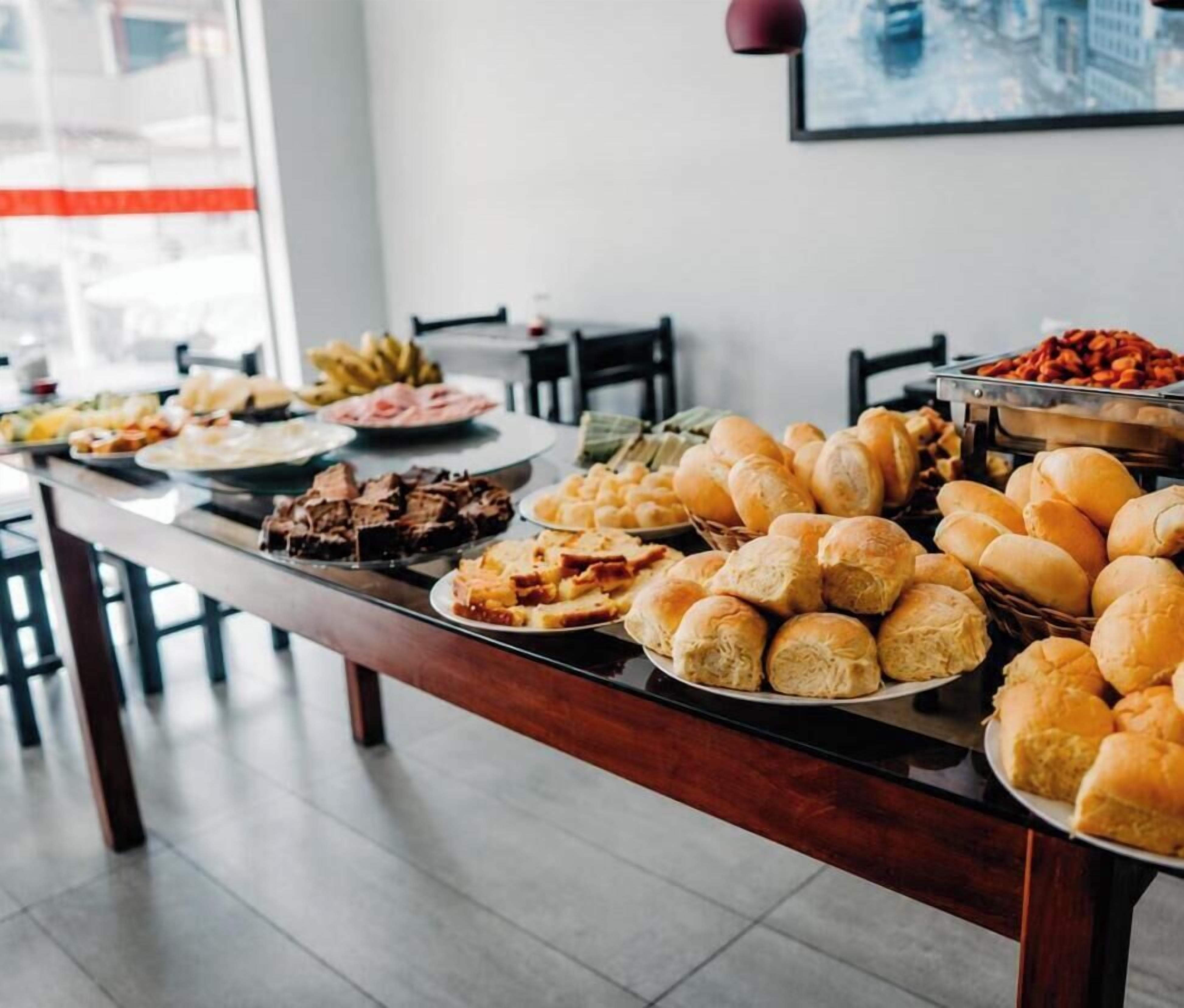 A buffet table with various food items including bread, pastries, and a meat dish.