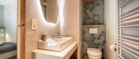 A modern bathroom with a wooden vanity, a sink, and a toilet.