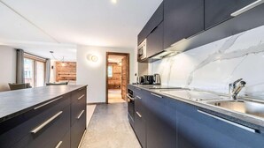 A modern kitchen with dark cabinetry, a marble countertop, and a stainless steel sink. - 1st floor, balcony, parking, tv, ski locker, 93m², Morzine (Morzine)