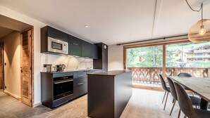 A modern kitchen with dark cabinetry, a marble countertop, and a large island. - 1st floor, balcony, parking, tv, ski locker, 93m², Morzine (Morzine)