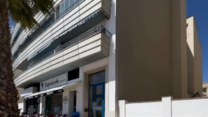 A modern building with a flat facade, a blue door, and a sign for 'Capriccio'. - Apartment Aguamarina 4B (Estepona)