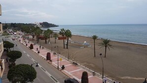 A coastal promenade with a beach, palm trees, and a road with vehicles. - Apartment Aguamarina 4B (Estepona)