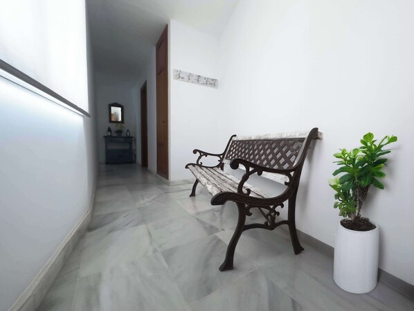 A hallway with a bench and a potted plant.