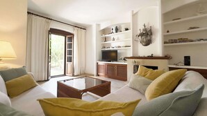 A living room with a sofa set, a coffee table, a television, and a fireplace. - Adosado junto al Mar (Estepona)