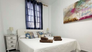 Ein Schlafzimmer mit einem Bett, zwei Nachttischen, einem Fenster mit Vorhängen und einem Wandbild.