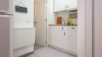 A kitchen with white cabinets, a tiled floor, and a sign that says "OPEN Beer HERE".