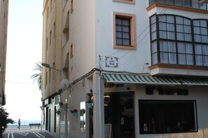 A street view with a building featuring a storefront with a striped awning and a sign that reads "Calle Real."