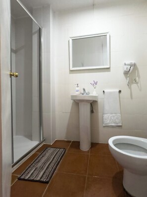 A bathroom with a glass shower door, a pedestal sink, a toilet, and a mirror above the sink. - Cristamar Center and Beach Apartment 2B (Estepona)